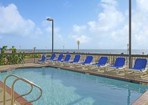 弗吉尼亚海滩碎浪度假酒店的一个带蓝色椅子的游泳池和海滩