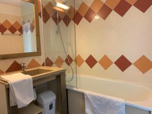 莱德萨阿尔卑斯travelski home classic - Résidence La Muzelle的浴室配有盥洗盆和浴缸。