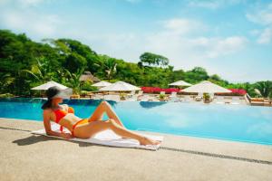克鲁兹德华纳卡克斯特尔Grand Matlali Riviera Nayarit的坐在游泳池旁毛巾上的比基尼女人