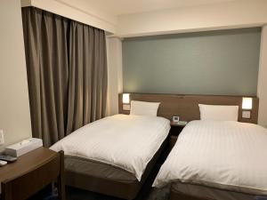 仙台仙台海滨通多米快捷酒店 的酒店客房设有两张床和窗户。