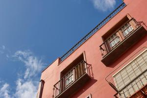 PuertoMaisonette Tazacorte的粉红色的建筑,设有两个阳台,享有蓝色的天空
