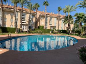 哈维亚Luxury Apartments Golden Beach Javea的棕榈树建筑前的游泳池