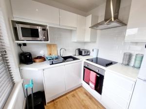 伯恩茅斯Bournemouth Luxury Apartment的白色的厨房配有水槽和微波炉