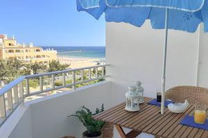波尔蒂芒Cozy beach front apartment的海滩阳台的桌子和遮阳伞