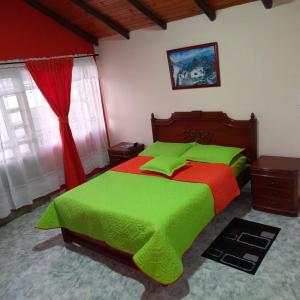 阿基塔尼亚Hospedaje Villa Isabel的一间卧室配有一张带绿色和红色床单的床