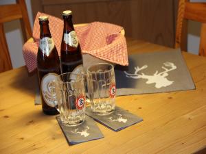 奥伯斯特多夫Casa Claudia - die schöne 4-Sterne-Fewo - im Sommer Bergbahntickets inclusive的2瓶啤酒和2杯桌子上的玻璃杯