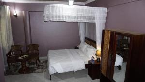 达累斯萨拉姆Jakicha Motel的卧室配有白色的床和2把椅子