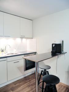 采尔马特Studio Omis的厨房配有白色橱柜、桌子和2把凳子