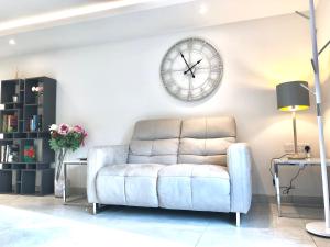 贝克韦尔Millstream Mews的客厅配有沙发和墙上的时钟