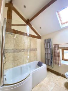 比代尔The Barn的浴室配有白色浴缸和淋浴。