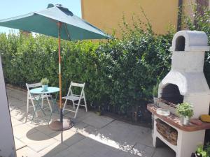 切塔尔多Poggio ai Grilli Apartment的一个带遮阳伞和户外烤箱的庭院