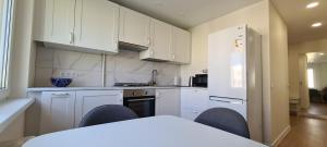 帕内韦日斯Sonata apartment的厨房配有白色橱柜和桌椅