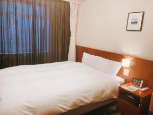 金泽Dormy Inn Kanazawa Natural Hot Spring的酒店客房设有白色的床和窗户。