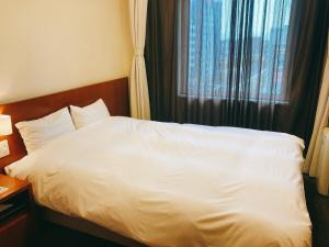 金泽Dormy Inn Kanazawa Natural Hot Spring的一间设有窗户的酒店客房内的一张白色床