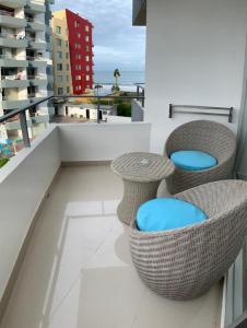 通苏帕Acogedor departamento junto al mar - Tonsupa的大楼内的阳台配有藤椅和桌子。