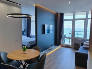 敖德萨Level 24 - Sea & Sky View Apartment的一间带桌子的客厅和一间带床的房间