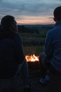 赫克瑟姆Wild Northumberland Glamping的两人在晚上坐在火坑周围