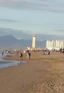 拉塞雷纳Departamento a pasos de la playa y centros comerciales的一群人在海滩上,有一座灯塔