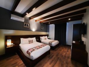 萨卡特兰Casa San Miguel Hotel Boutique y Spa的酒店客房设有两张床和电视。