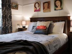 赫本温泉维奥拉赫本温泉度假屋的一间卧室配有一张带枕头的床,墙上挂有图片