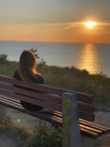 桑日卡Гостевой дом的坐在长凳上观看日落的女人