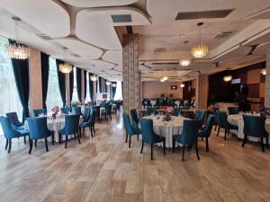 克卢日-纳波卡Ramada by Wyndham Hotel Cluj的用餐室配有白色的桌子和蓝色的椅子