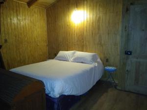 比亚里卡Cabaña entre Arboles的卧室配有白色床,墙上有灯