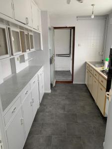 上敏斯特5 Bedroom House with outdoor space的厨房配有白色橱柜和瓷砖地板。