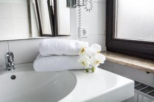 纽伦堡Hotel Avenue Altenfurt的浴室水槽配有毛巾和鲜花