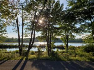 GouldsboroPocono mountain hotel and spa的阳光照耀着树木的湖泊美景