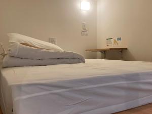 弘前市HOSTEL HIROSAKI - Vacation STAY 66581v的一张白色的床,位于带桌子的房间