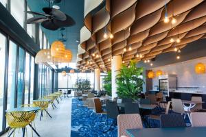 黄金海岸Rydges Gold Coast Airport的餐厅设有桌椅和大窗户。