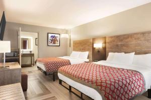 博林格林Days Inn & Suites by Wyndham Bowling Green的酒店客房设有两张床和电视。