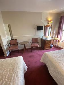 纳斯茅那汉海港酒店的酒店客房带两张床和一张桌子以及椅子。