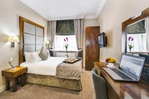 伦敦Gem Langham Court Hotel的酒店客房配有一张床、一张书桌和一台笔记本电脑