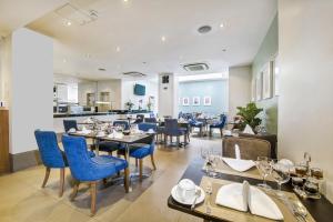 伦敦Gem Langham Court Hotel的一间在房间内配有蓝色椅子和桌子的餐厅