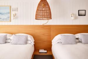 南雅茅斯Bluebird Parker Beach Lodge的一间设有两张床和一盏墙上灯的房间