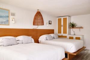 南雅茅斯Bluebird Parker Beach Lodge的配有白色床单的客房内的两张床