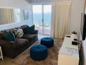 乌姆德洛蒂Sands Beach Breaks Umdloti Beach View的客厅配有沙发和2个蓝色的搁脚凳