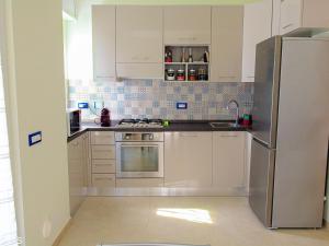 皮特拉利古Pietra Home, posto auto, AC ,WIFI, 150mt dal mare的厨房配有白色橱柜和不锈钢冰箱