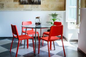 瓦莱塔Valletta Collection - St Pauls Apartment的一间用餐室,配有红色的椅子和桌子