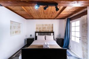 瓦莱塔Valletta Collection - St Pauls Apartment的一间卧室设有一张带木制天花板的大床