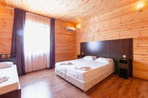皮聪达AMSHIN-Pitsunda的木制客房内的一间卧室配有一张大床