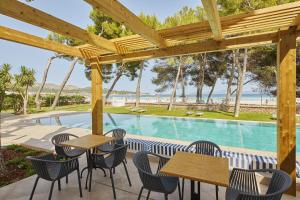 阿尔库迪亚港Sofia Alcudia Beach的一个带桌椅的庭院和一个游泳池