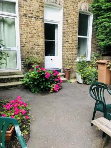 伦敦Amhurst Hotel的一座建筑前带两把椅子和鲜花的庭院