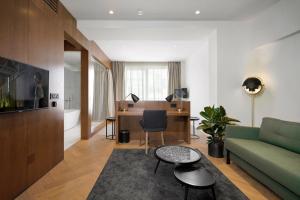 贝尔格莱德Dominic Smart & Luxury Suites - Edition的客厅配有绿色沙发和书桌