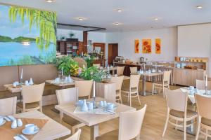 普劳西Ferienanlage - Zum See的餐厅设有桌椅和大窗户。