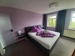阿多夫威斯洛布兰德酒店的一间卧室设有紫色的墙壁和一张带紫色枕头的床