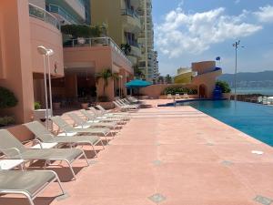 阿卡普尔科Comfortable Beachfront apartment in Acapulco的游泳池旁的一排躺椅