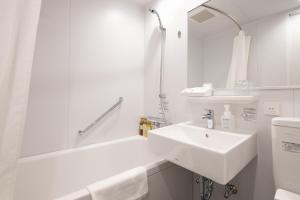 仓敷Hotel Grand Cocoe Kurashiki的白色的浴室设有水槽和浴缸。